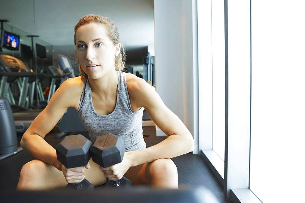 Serious woman lifting weights in gym