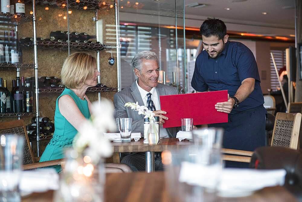 Waiter assisting couple with menu in restaurant