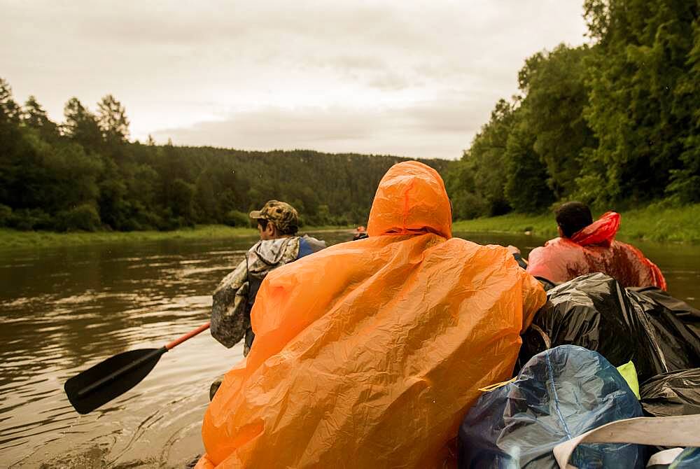 People wearing ponchos on boat in river