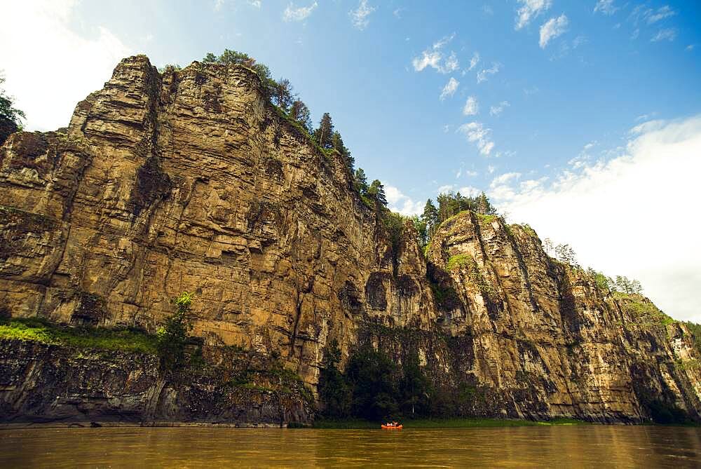 Distant boat on river near cliff