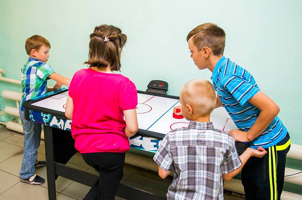 Caucasian children playing air hockey