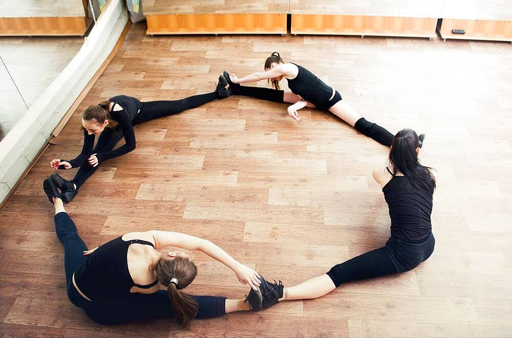 Caucasian dancers stretching in studio