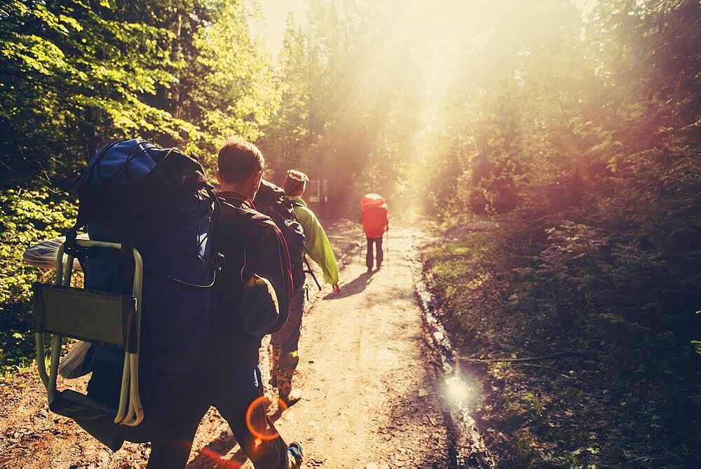 Backpackers hiking on dirt path in forest