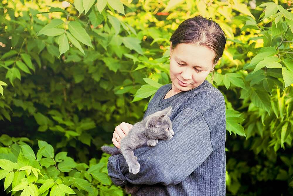 Caucasian woman petting cat in garden