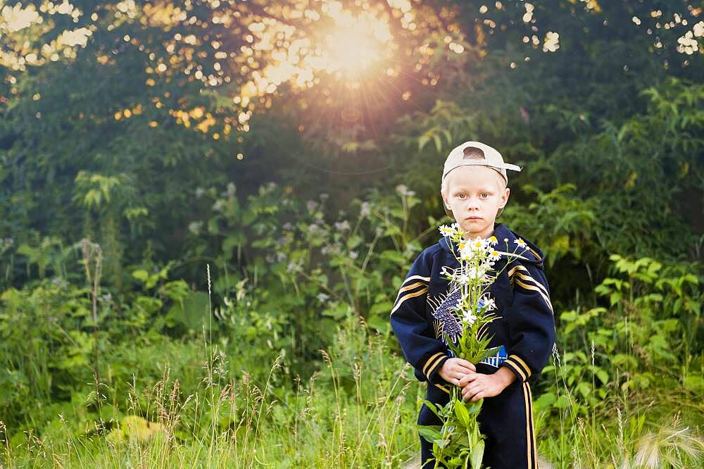 Caucasian boy picking flowers in rural field