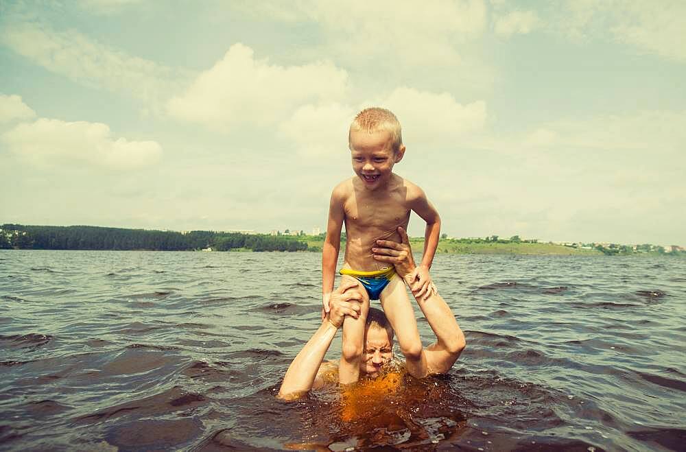 Caucasian father and son swimming in lake