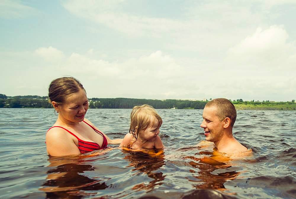 Caucasian family swimming in lake