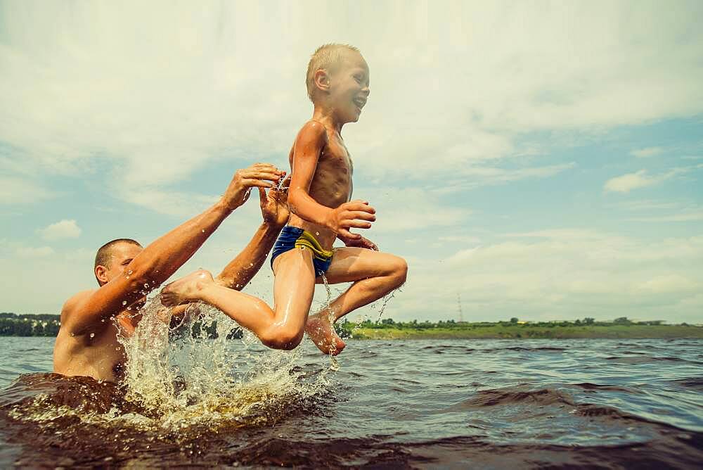 Caucasian father and son swimming in lake