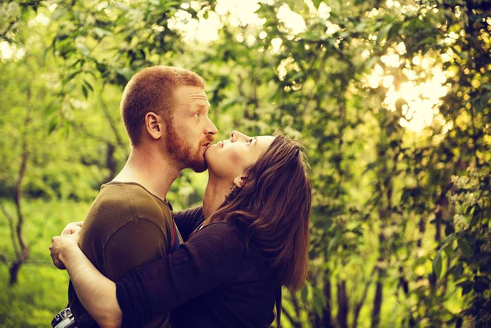 Caucasian couple hugging near trees