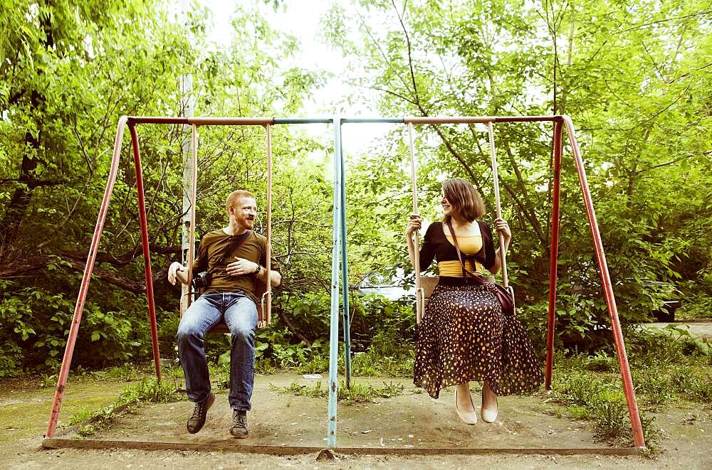 Caucasian couple playing on swing set