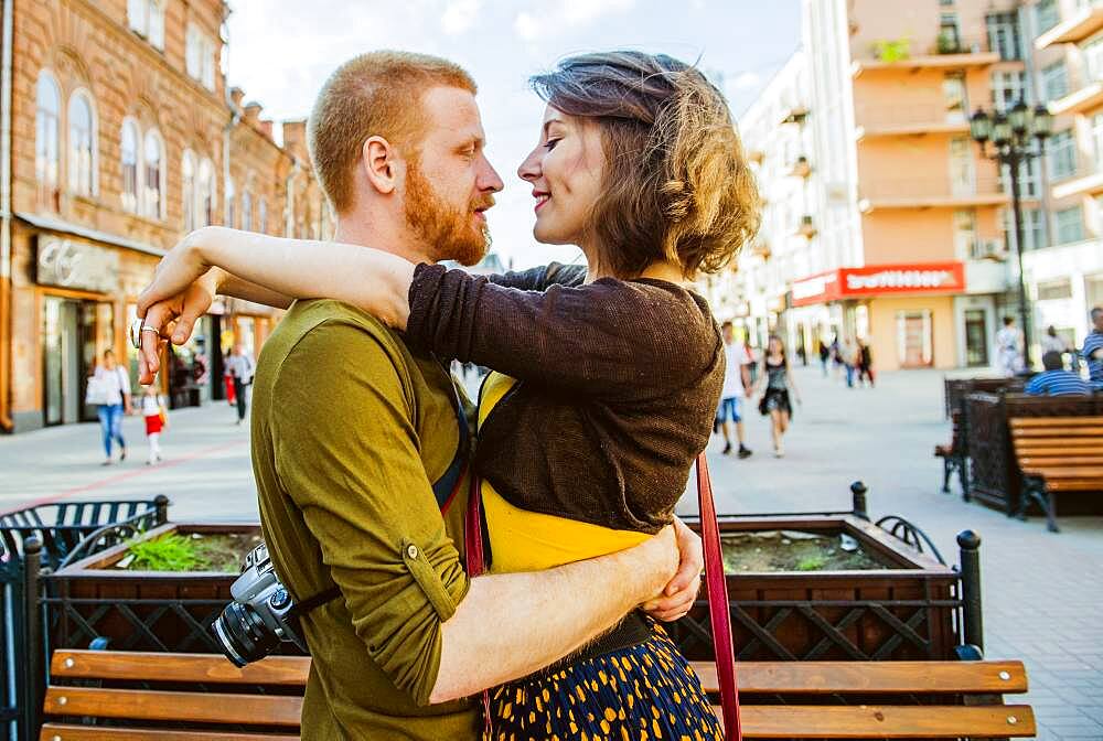 Caucasian couple hugging in city