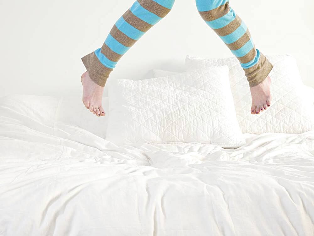 Caucasian woman jumping on bed