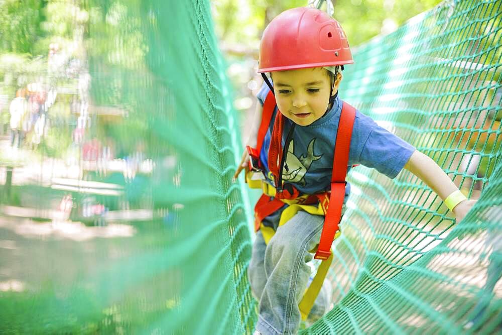 Caucasian boy in harness climbing on net