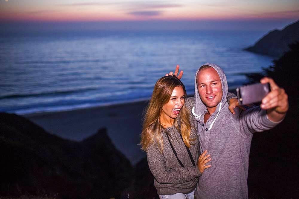 Caucasian couple taking selfie at beach