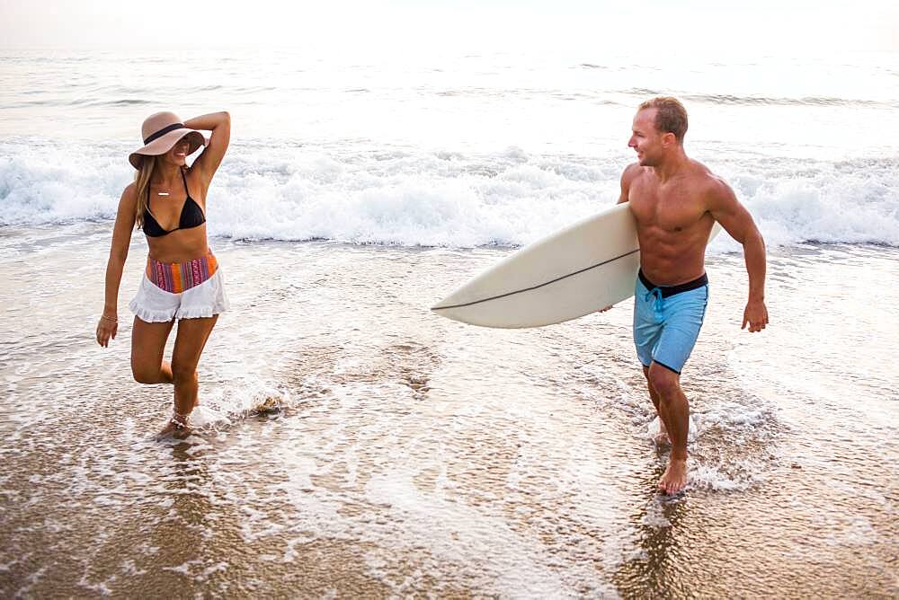 Caucasian couple in waves on beach