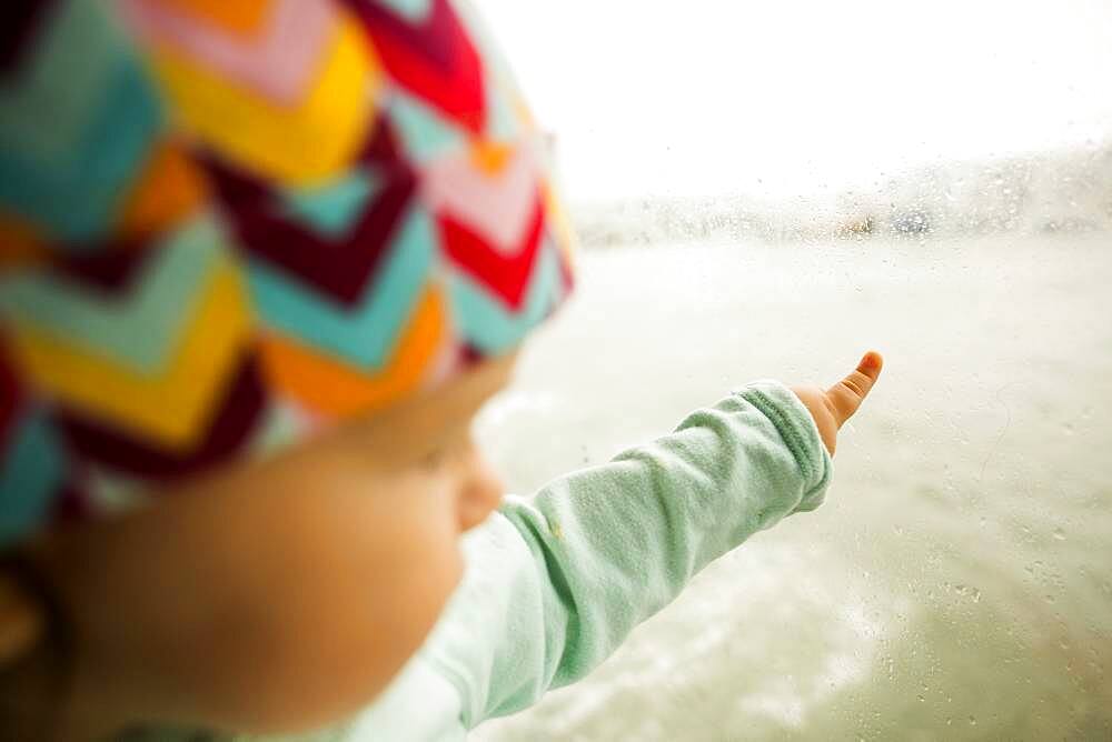 Caucasian baby girl pointing at ocean from window