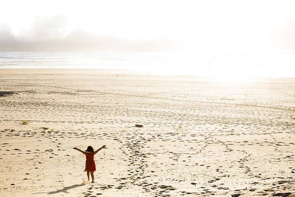 Caucasian girl standing with arms outstretched on beach