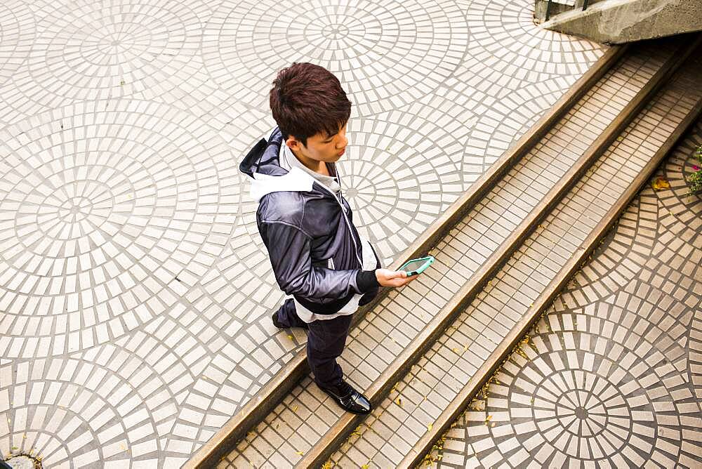 Asian man using cell phone in courtyard