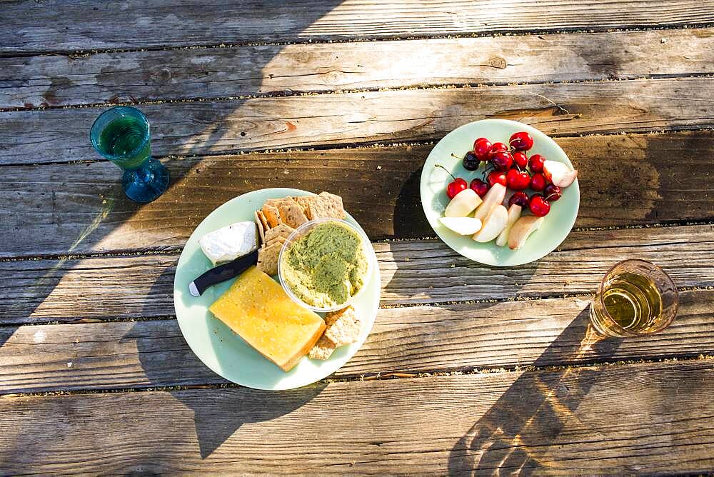 Plates of cheese and fruit on wooden table