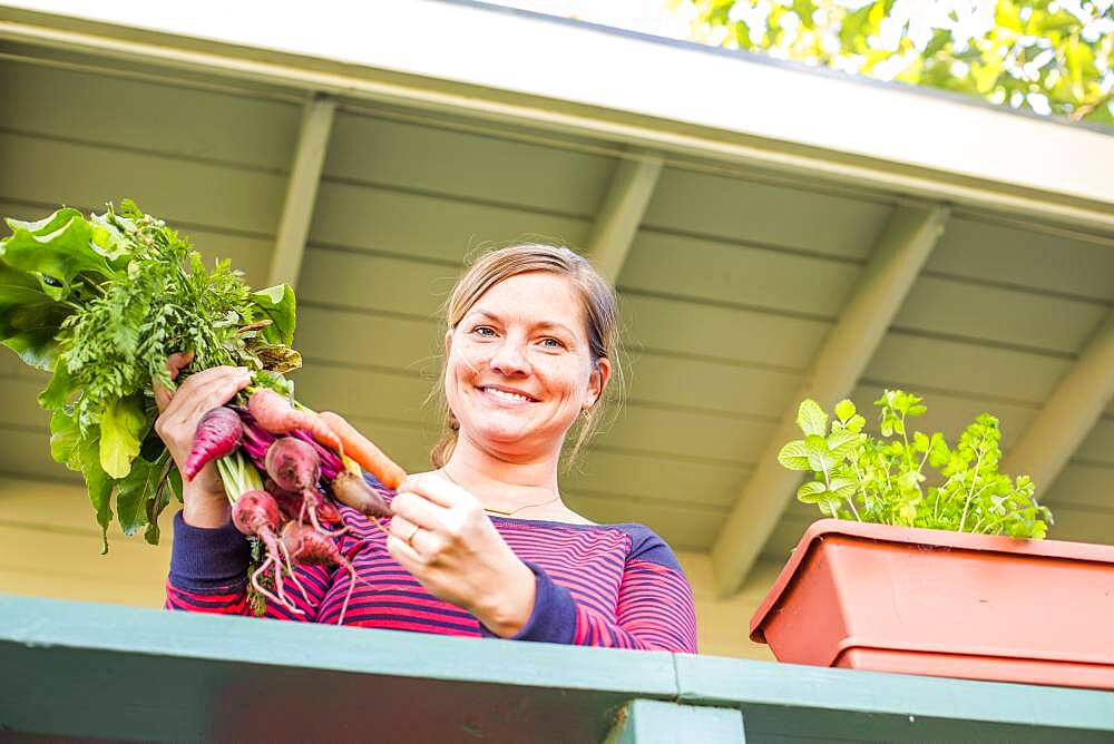 Caucasian woman holding fresh carrots on patio