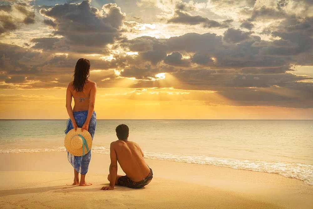 Caucasian couple admiring sunset on beach