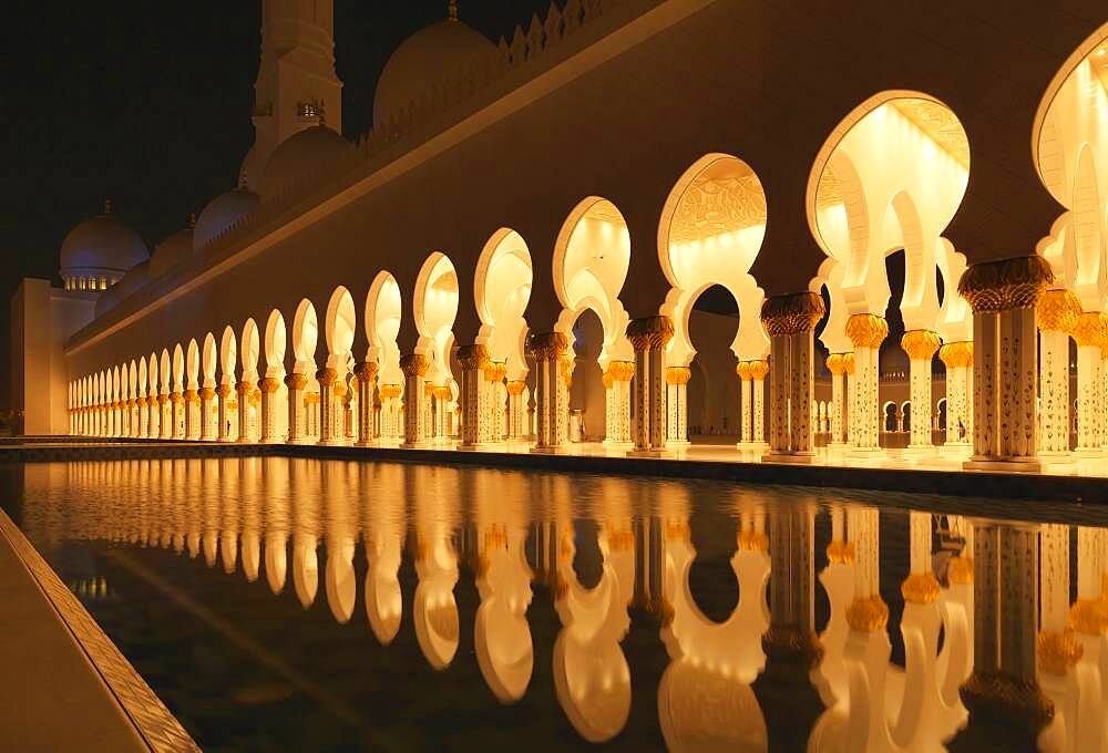 Illuminated colonnade reflecting in still pool