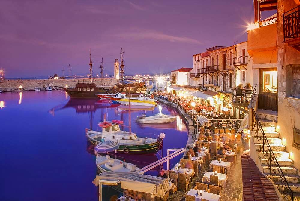 Boats docked in urban harbor at night