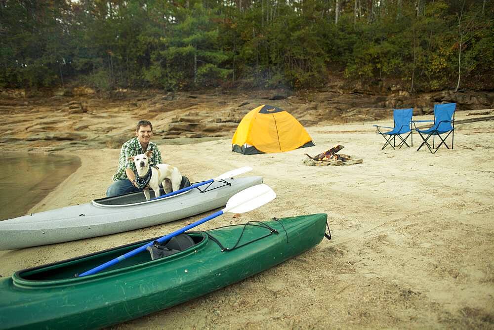 Man and dog with kayak at campsite