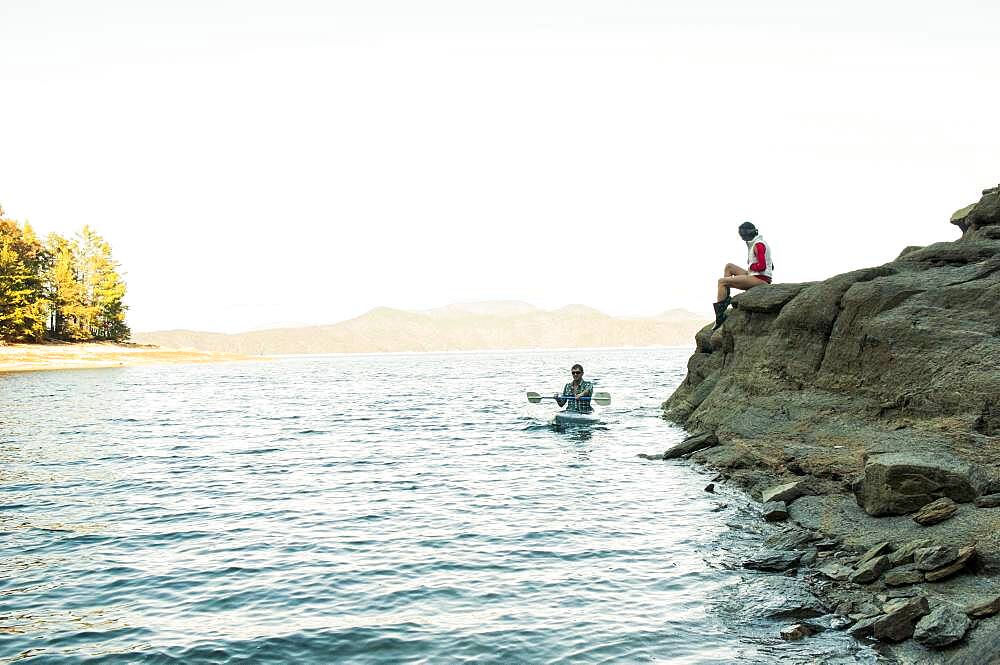 Woman watching boyfriend rowing kayak in lake