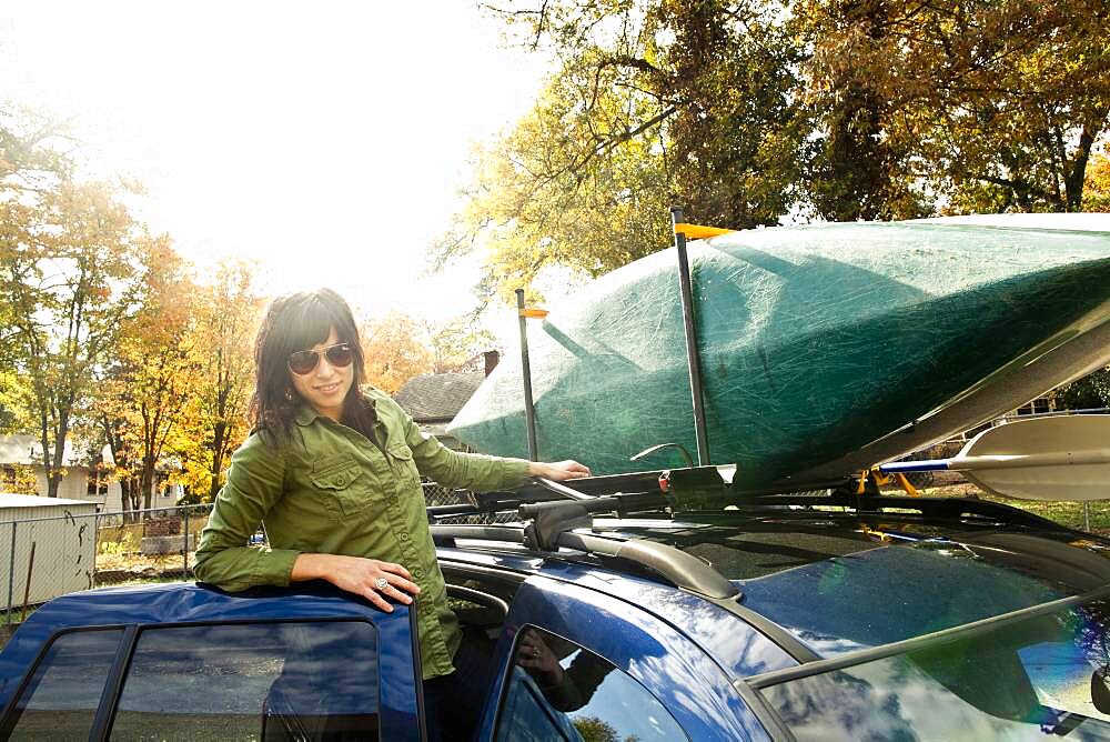 Caucasian woman packing kayak on car