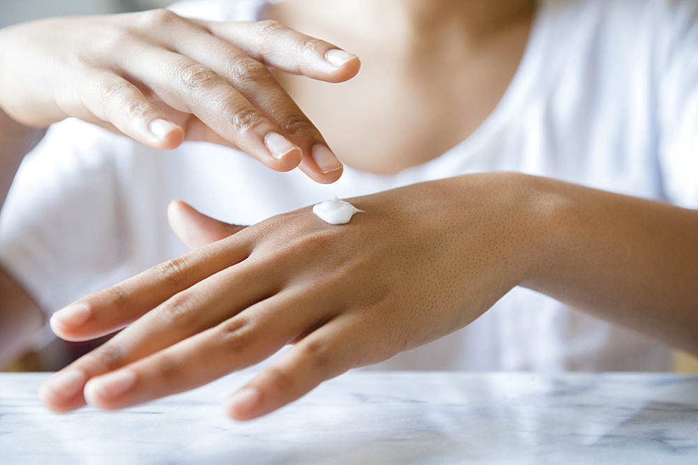 African American woman applying lotion to hand