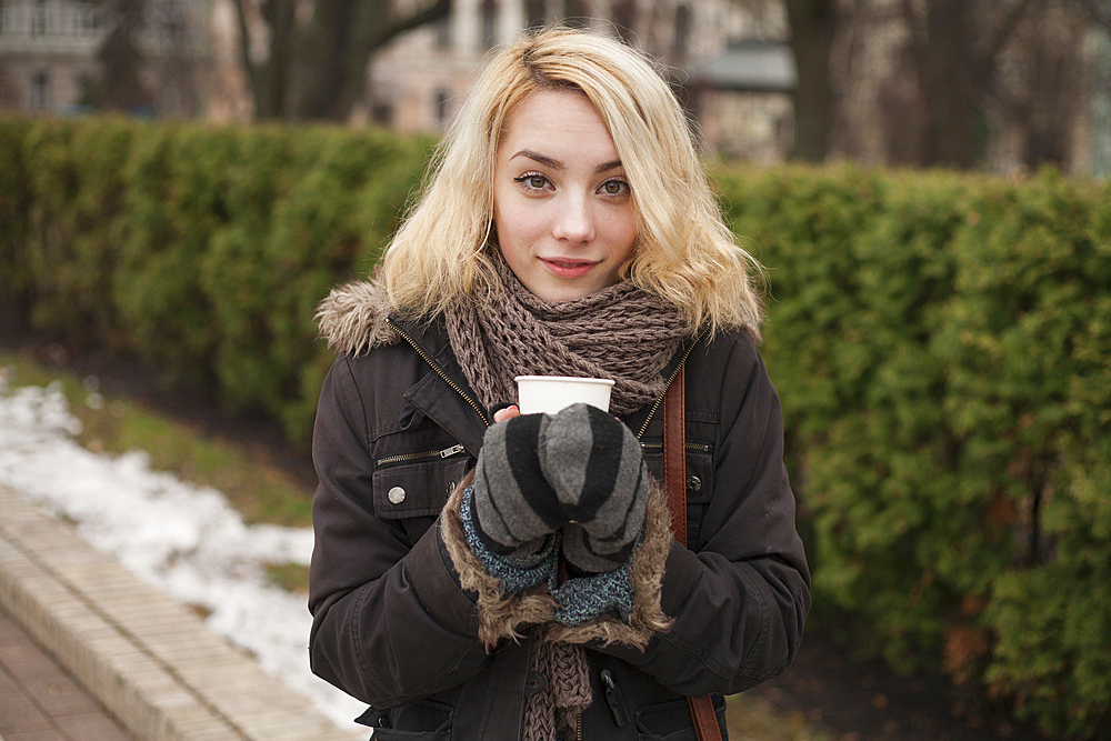 Caucasian woman warming hands on cup of coffee