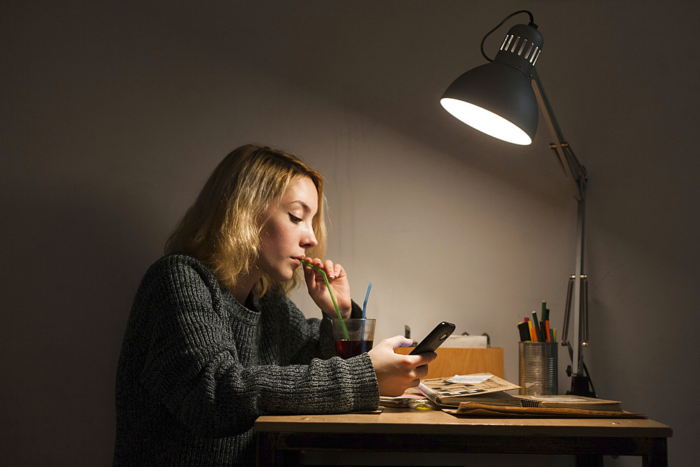 Caucasian woman drinking beverage and texting on cell phone