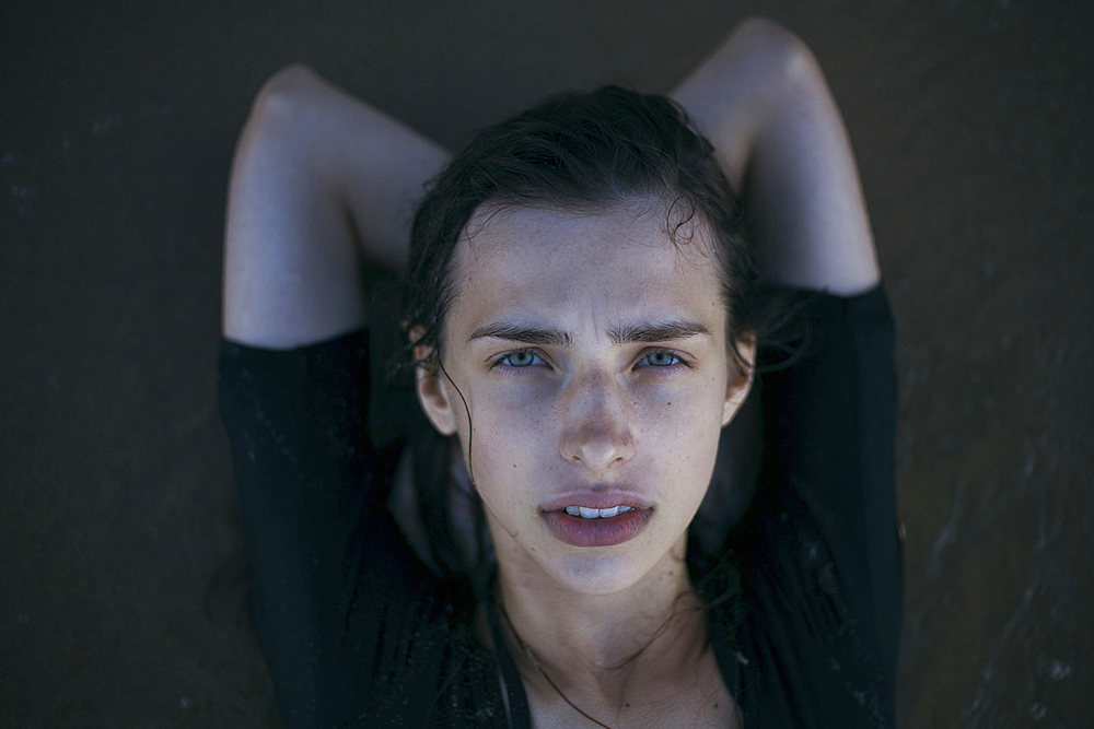 Caucasian woman laying on beach in waves