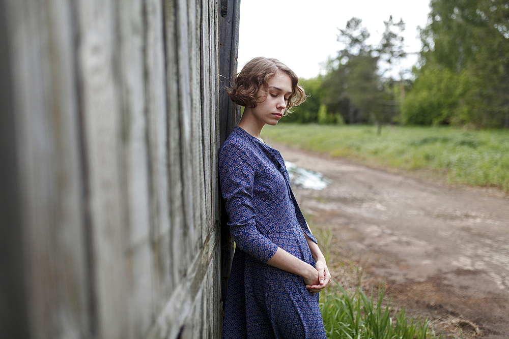 Pensive Caucasian woman leaning on wooden fence