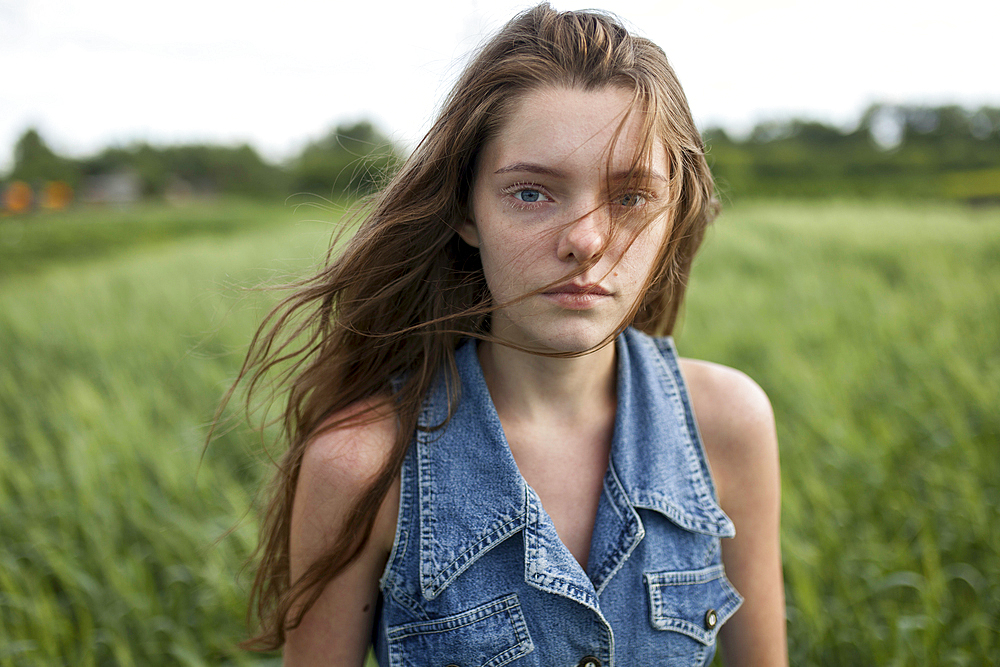 Wind blowing hair of Caucasian woman in field