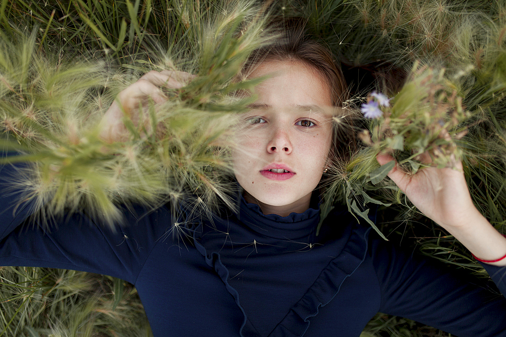 Serious Caucasian girl laying in field