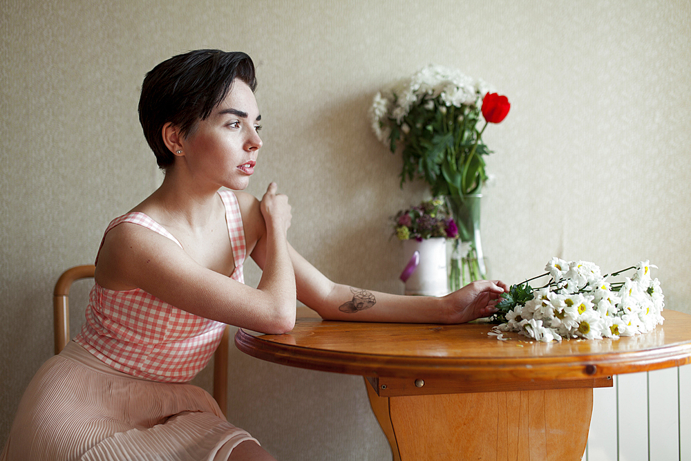 Pensive Caucasian woman sitting at table with flowers