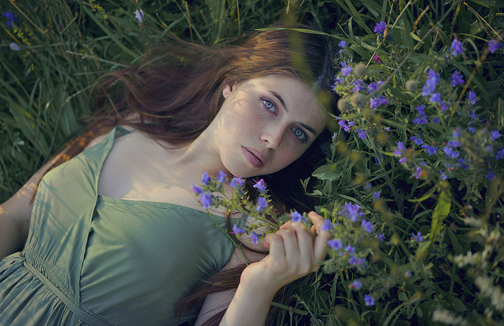 Caucasian woman laying in grass with wildflowers