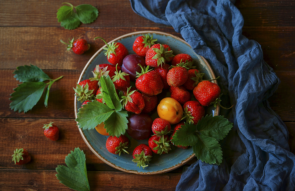 Strawberries and plums on plate