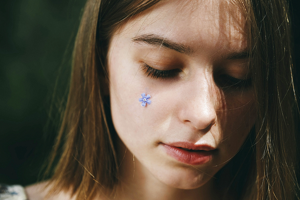 Caucasian woman with flower jewelry on cheek