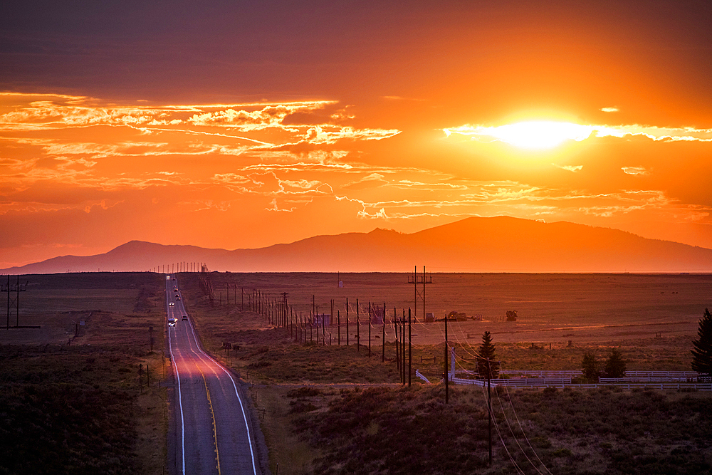 Cars driving on remote road at sunset