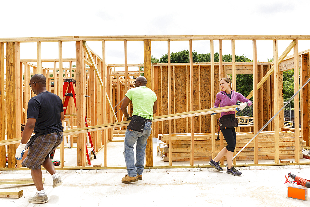 Volunteers carrying lumber at construction site