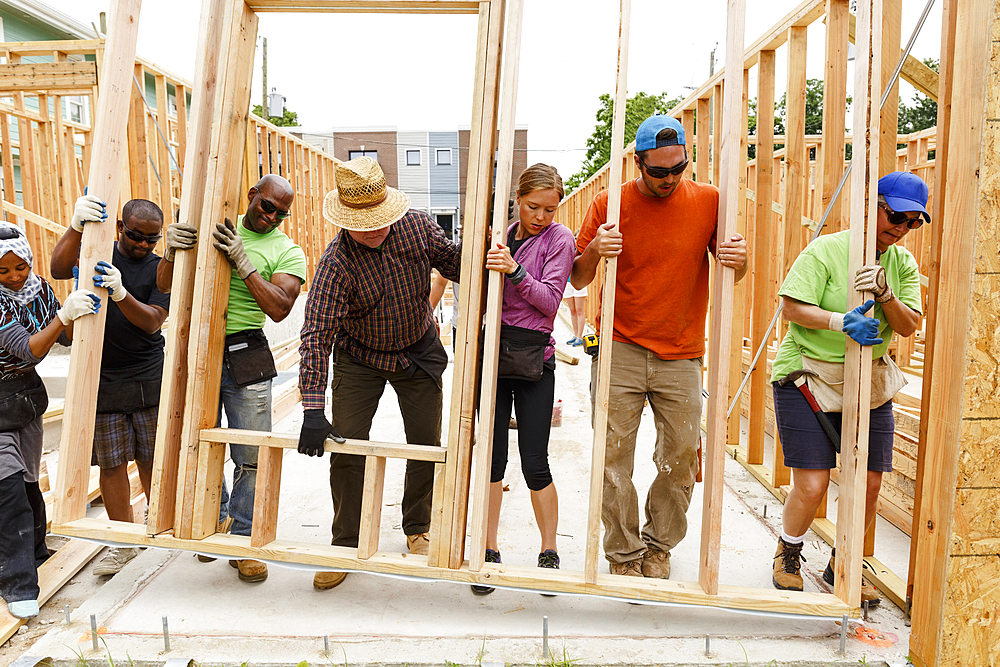 Volunteers lifting wall at construction site