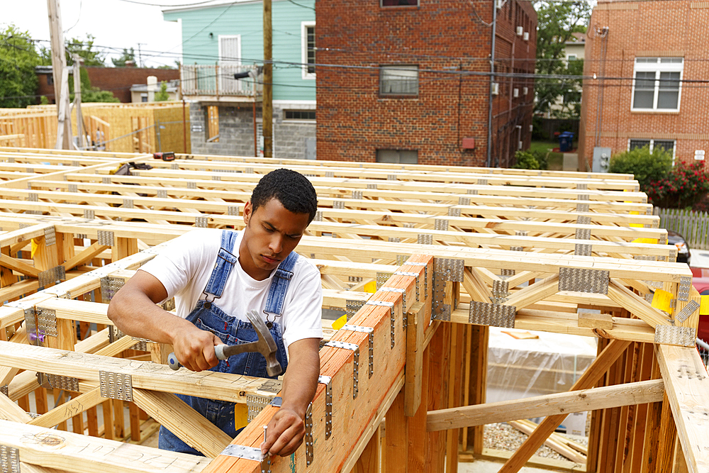 Mixed race man hammering nail at construction site