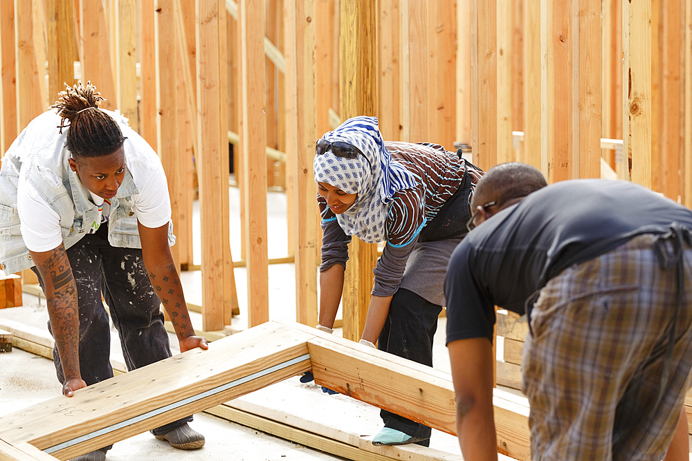 Volunteers lifting wooden frame at construction site