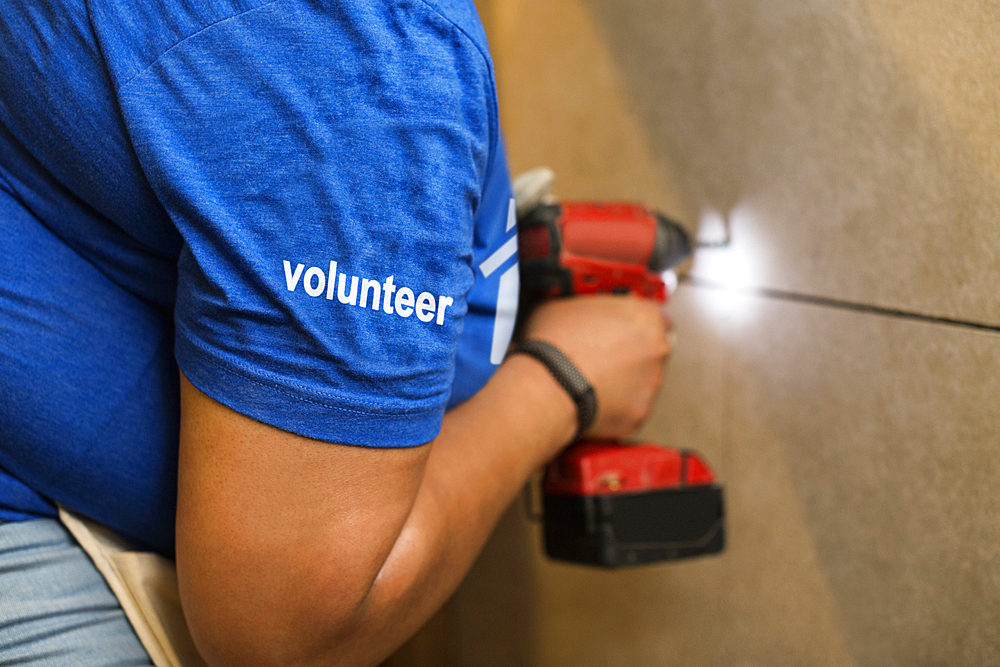 Volunteer black woman drilling wall