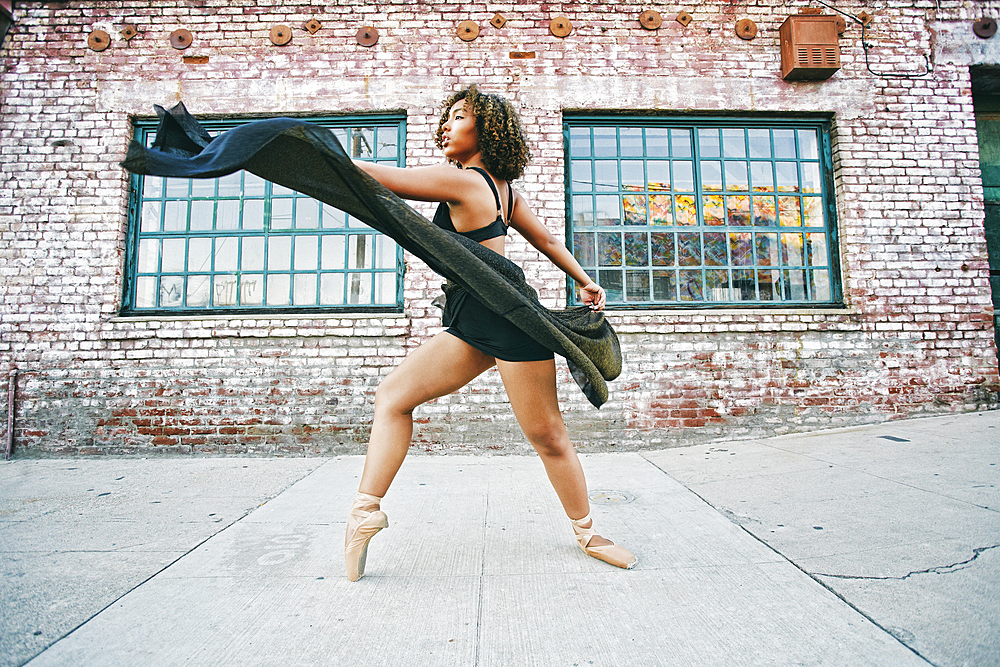 Mixed race woman dancing ballet on sidewalk