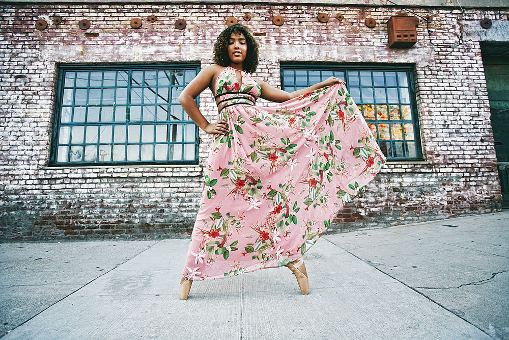 Mixed race ballet dancer wearing dress on sidewalk