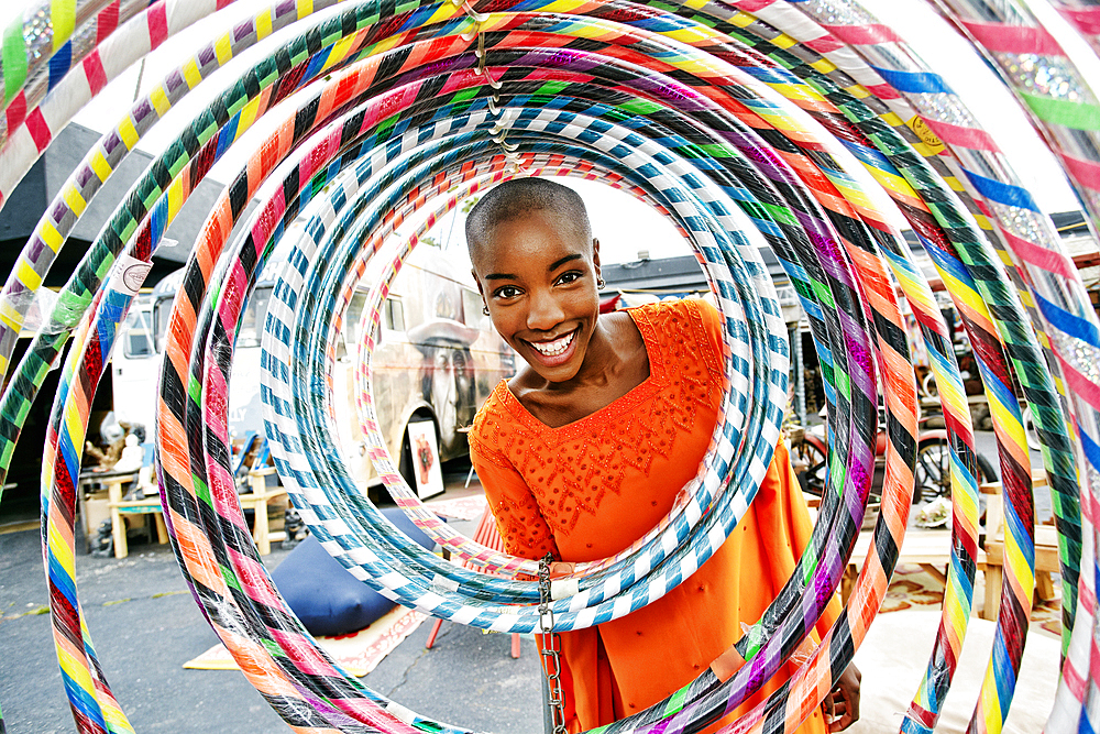 Portrait of smiling bald black woman behind hoops